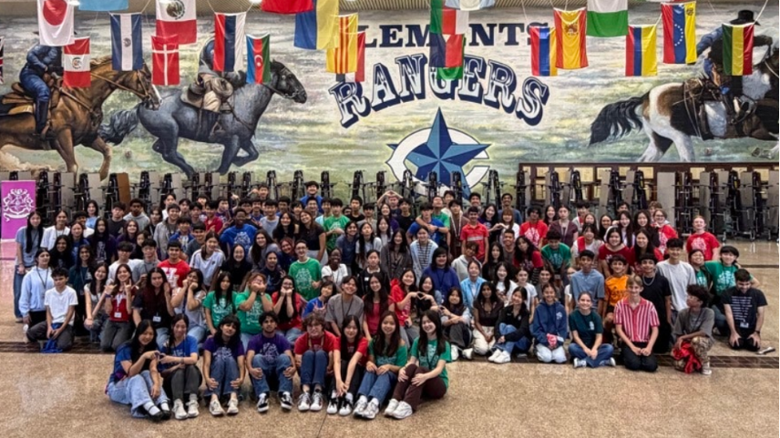 Students in high school cafeteria pose for a group photo after social event.